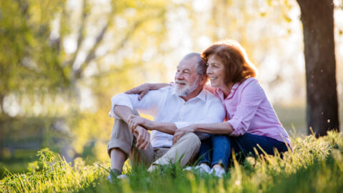 Beautiful senior couple outside in spring nature, hugging.