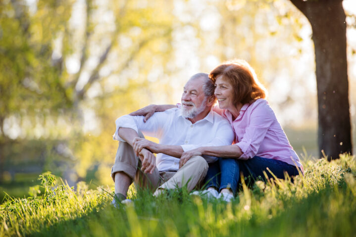 Beautiful senior couple outside in spring nature, hugging.